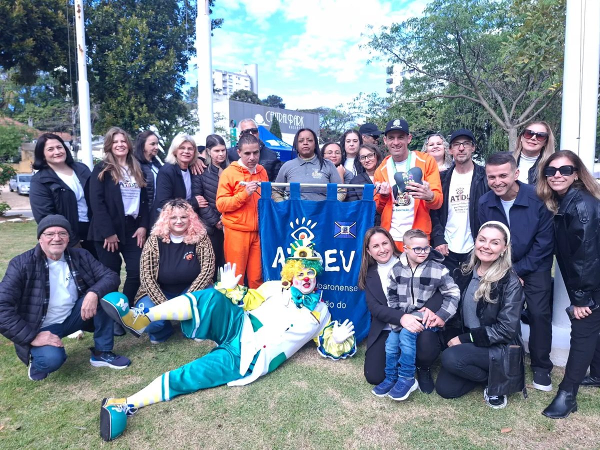 Equipe, alunos e voluntários da ATIDEV reunidos em grupo ao ar livre, com uma placa da associação, no desfile de 7 de Setembro