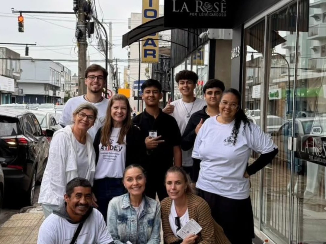 Equipe e voluntários da ATIDEV de camiseta branca reunidos na rua durante o Pedágio Solidário