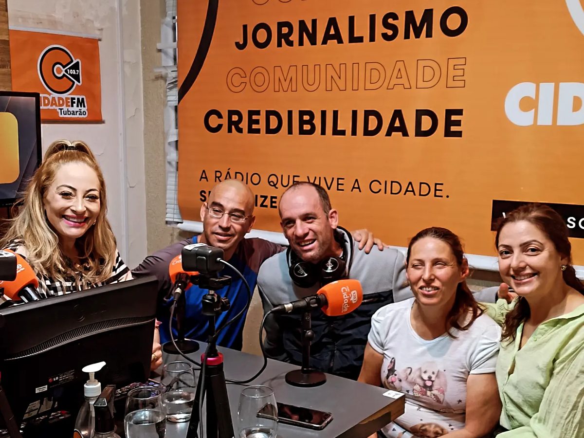 Alunos do projeto Em Cena sorrindo durante entrevista em estúdio de rádio